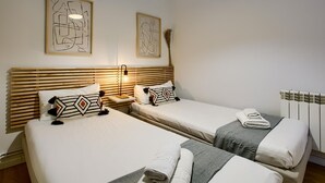 Ein Hotelzimmer mit zwei Betten, einem Holzkopfteil, einem Nachttisch mit Lampe und abstrakter Kunst an der Wand.
