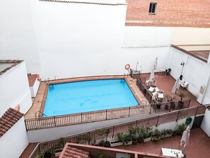 A rooftop swimming pool with a metal railing, surrounded by potted plants and outdoor furniture. - Plaza Mayor II - Two-bedroom apartment (Madrid)