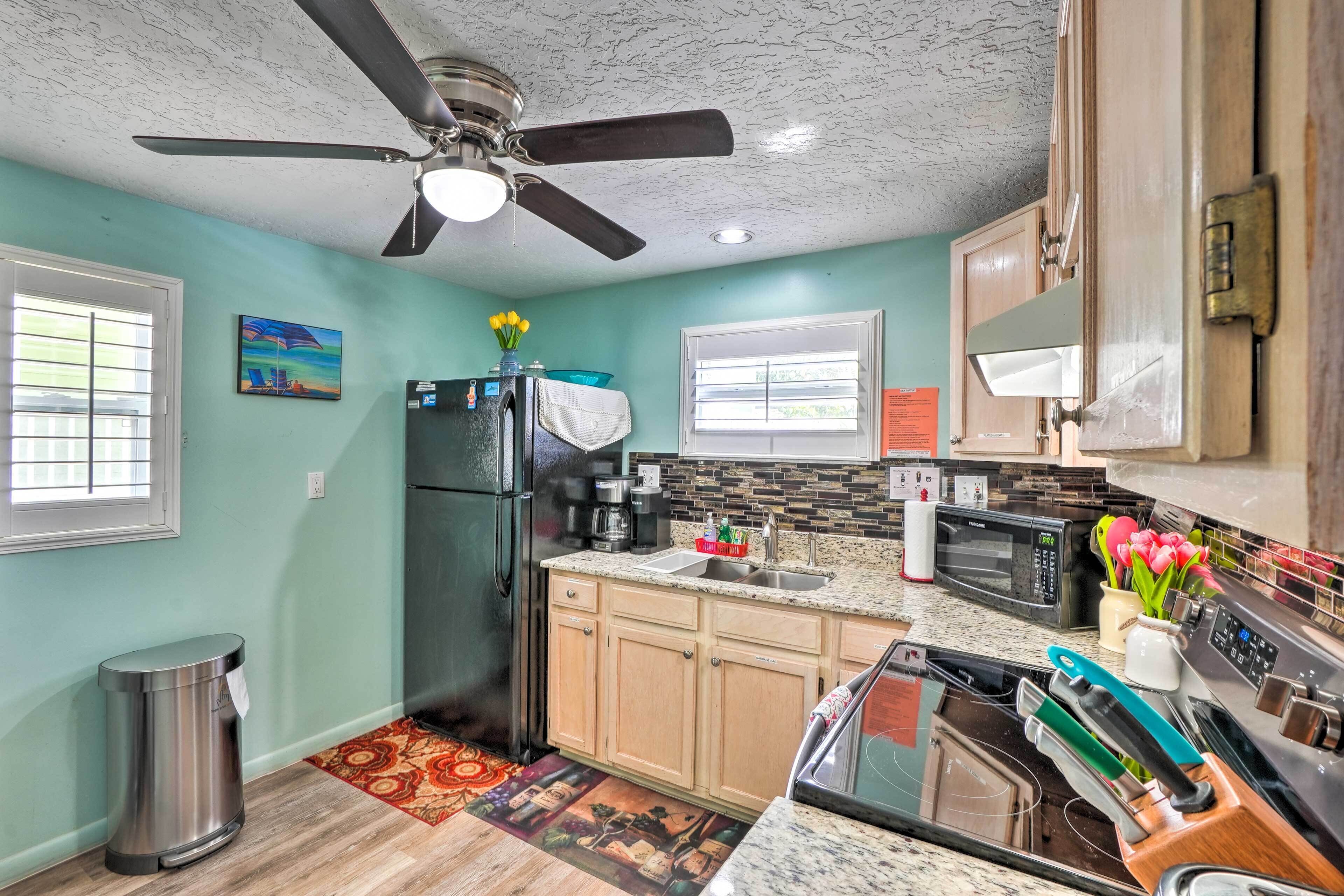A kitchen with a refrigerator, microwave, sink, and stove.