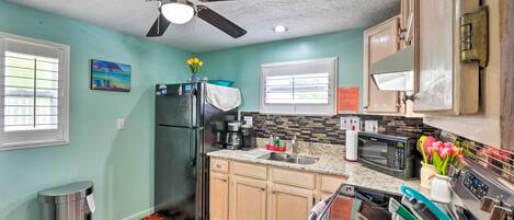 A kitchen with a refrigerator, microwave, sink, and stove.