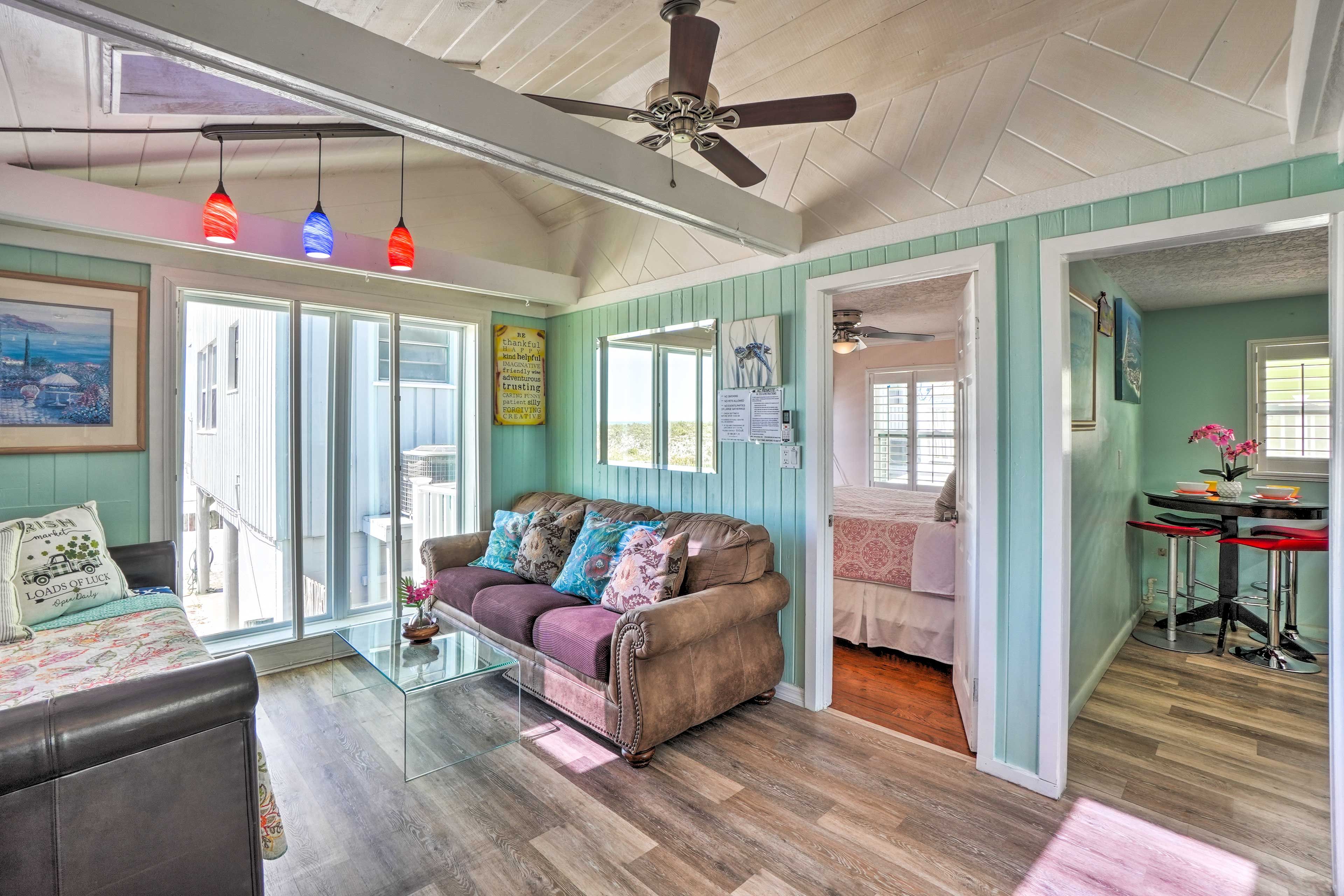 A cozy living room with a sofa, glass coffee table, and a ceiling fan.