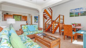 A living room with a sofa, coffee table, and dining area with chairs and a table.