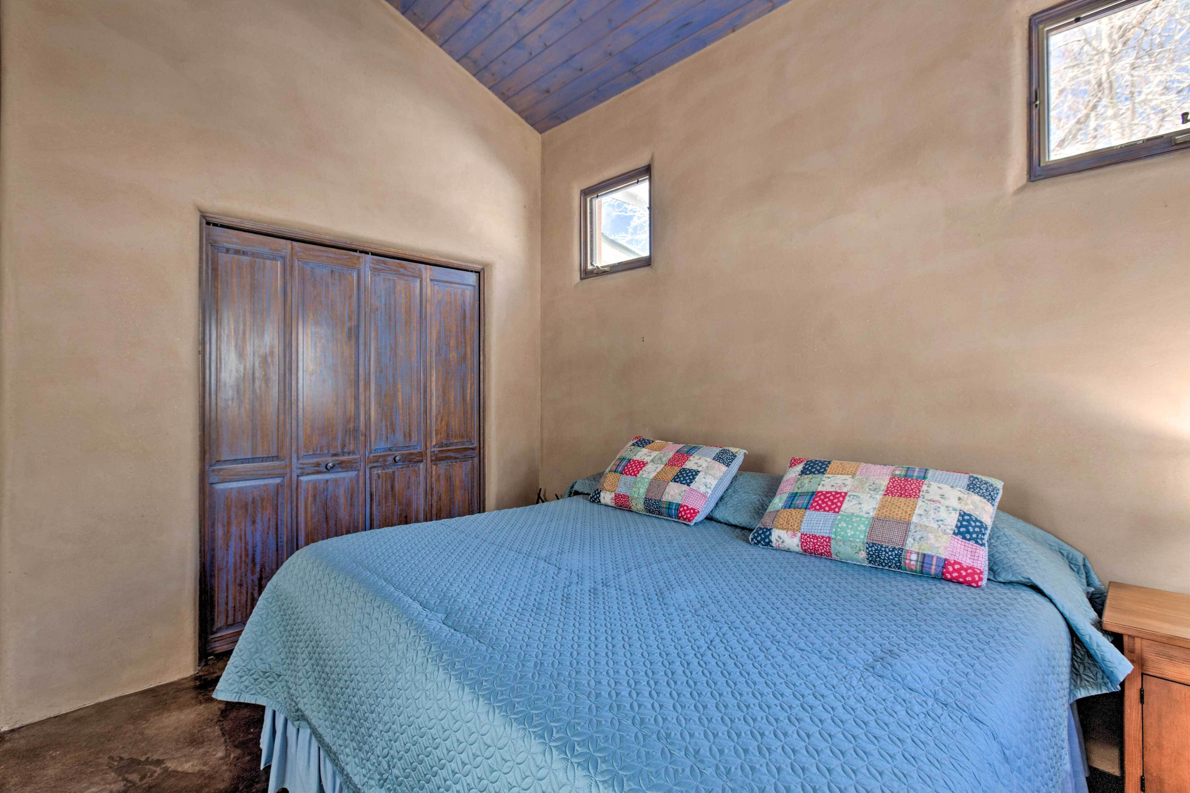 Een slaapkamer met een groot bed, een houten garderobe en een klein raam.