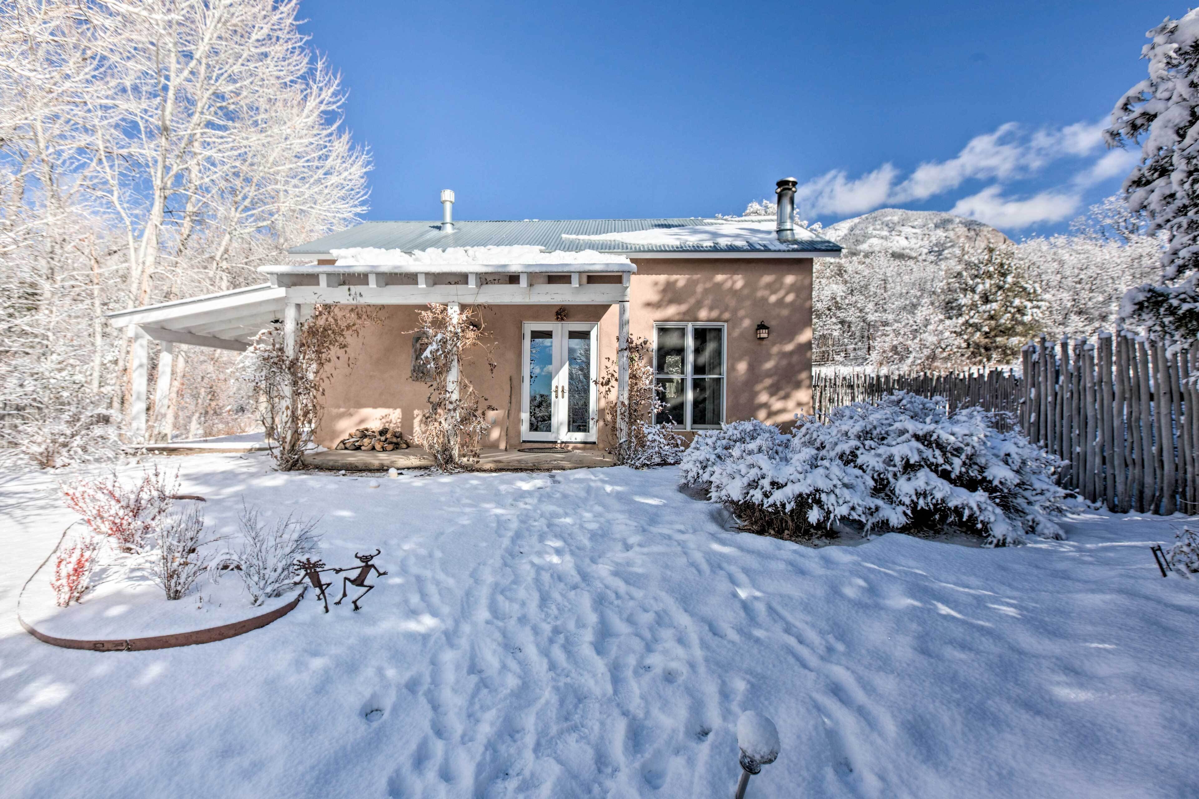 A house with a covered porch, a snow-covered yard, and a wooden fence.