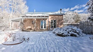 A house with a covered porch, a snow-covered yard, and a wooden fence.