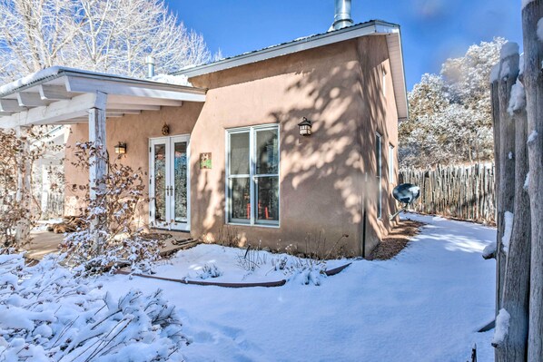 Una casa de un piso con fachada color beige, un porche cubierto y un patio cubierto de nieve.