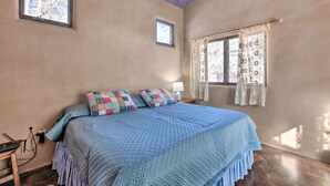 A bedroom with a large bed, two windows, and a wooden ceiling.