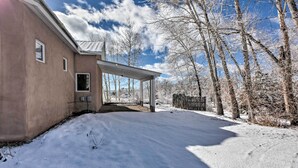 A snow-covered driveway leading to a house with a covered porch and a wooden fence.