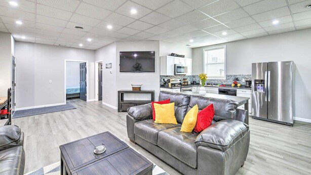 A modern living room with a leather sofa, a coffee table, and a kitchen area with stainless steel appliances.