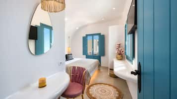 Un baño moderno con un lavamanos blanco, un espejo, un tocador, una silla y una cama con contraventanas azules.