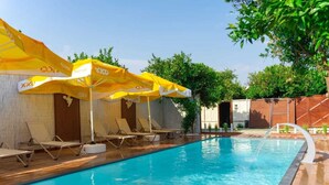A swimming pool with yellow umbrellas, lounge chairs, and a wooden deck.