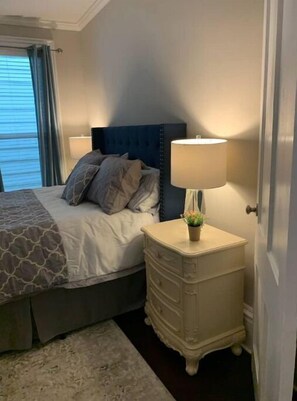 Restful retreat with a neatly made bed, bedside table, and potted plant.