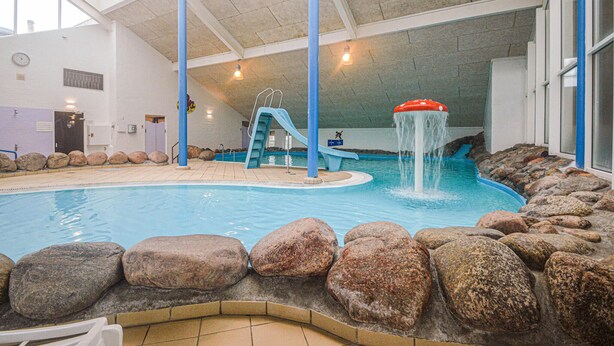An indoor swimming pool with a slide, rock formations, and a water fountain. - Nice apartment in Hemmet with sauna (Hemmet)