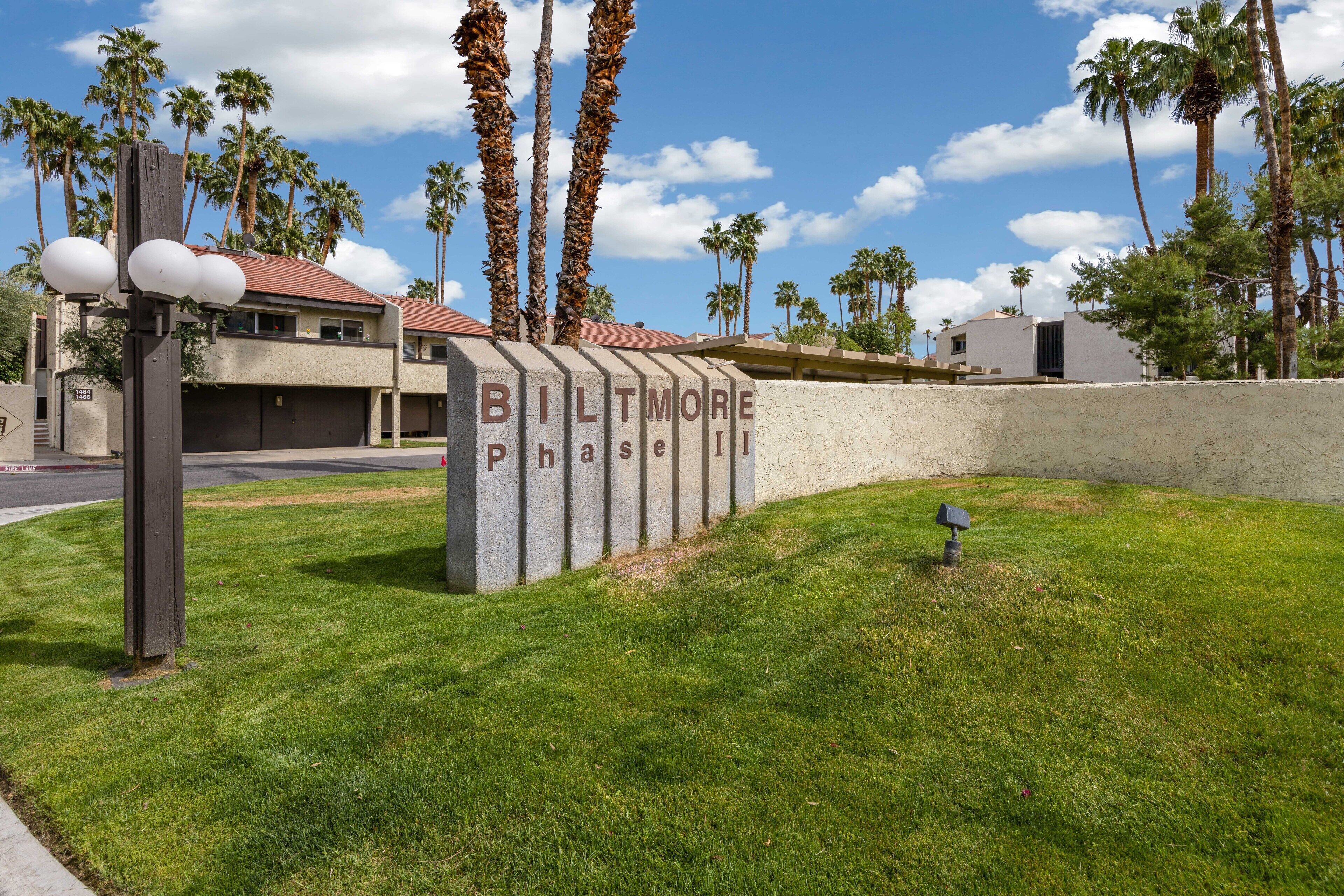 A sign for 'Biltmore Phase II' with a grassy area and palm trees in the background.
