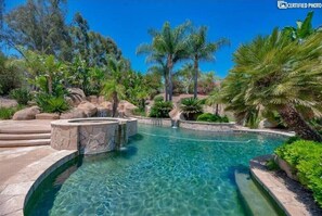 Relax by the serene pool surrounded by lush greenery and palm trees.