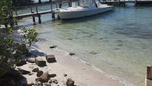 Ein Boot liegt an einem Steg, im Hintergrund ist eine Brücke und klares Wasser zu sehen.