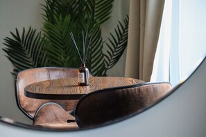 Relax in a stylish setting with a curved chair and small table, accompanied by a bottle and decorative diffuser.