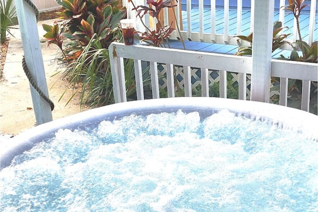 A hot tub with water, surrounded by a wooden deck and plants.