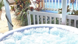 Ein Whirlpool mit Wasser, umgeben von einer Holzterrasse und Pflanzen.