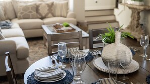 Un coin repas avec une table ronde dressée pour le repas, un canapé en arrière-plan et un vase décoratif sur la table.