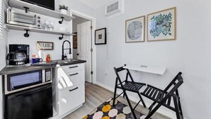 A compact kitchen with a microwave, coffee maker, and a small dining area with a chair and table. - Tropical Tiny house with Outdoor jacuzzi & Gazebo (Tampa)