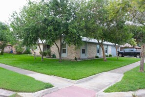 Un barrio residencial con una casa, un camino de entrada y una acera.
