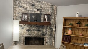 A dining area with a stone wall, a fireplace, and a wooden bookshelf. - Chill Suburban Get Away (Corpus Christi)