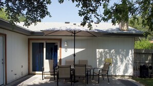 A patio with a table and chairs, a covered area, and a door leading to a covered entryway. - Chill Suburban Get Away (Corpus Christi)