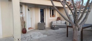 Un espace extérieur abrité comprenant un canapé, une petite table et une plante en pot.