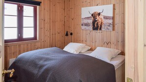 A wooden-paneled room with a bed, a window, and a picture of a bull on the wall. - Stunning home in Gol with sauna (Gol)