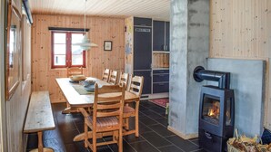A cozy cabin interior with a dining table, chairs, a bench, a wood-burning stove, and a window with a view. - Stunning home in Gol with sauna (Gol)