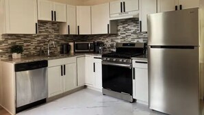 Una cocina moderna con armarios blancos, un refrigerador de acero inoxidable, un horno empotrado y un microondas.