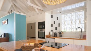 A modern kitchen with a wooden countertop, stainless steel appliances, and a decorative hanging light fixture. - Villa Secrète, hidden from view and close to beaches and shops (Saint-François)