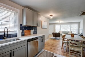 A modern kitchen with grey cabinets, a dishwasher, and a wooden countertop. There is a dining area with a table and chairs, and a living room with a sofa and a coffee table. - Renovated 2 BR home close to Lancaster attractions (Lancaster)