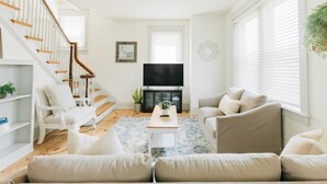 Un salon avec un escalier, un téléviseur à écran plat et une cheminée.