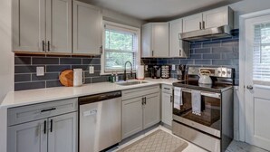 A modern kitchen with grey cabinets, a stainless steel range hood, a dishwasher, and a double oven. - New cozy home near Outlets & Amish Country (Lancaster)