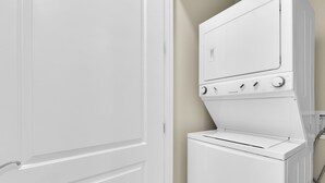 A white washer and dryer unit with a control panel, positioned against a wall with a door to the left. - Newly Remodeled 2BR/2B Condo (South Padre Island)