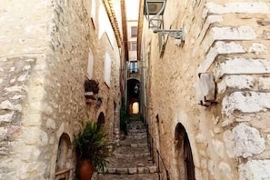 A narrow stone staircase in a historic building with arched doorways and a lantern above. - LE CARNOT Apartment for 2 By Sunset (Antibes)