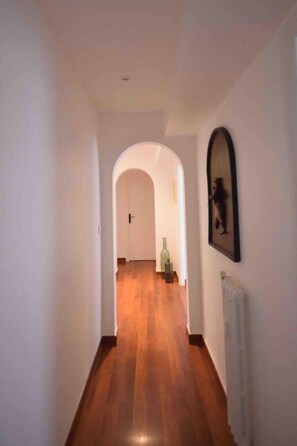 Leading to a space, this hallway features a door at the end and a framed picture on the wall.