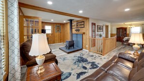 A spacious living room with a fireplace, wooden furniture, and a large rug.