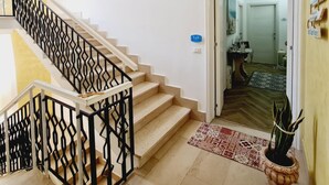 A staircase with a geometric railing, a patterned rug, and a potted plant. - Appartamento lu Ientu (Porto cesareo)