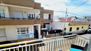 A balcony with outdoor furniture, a view of a building with a pool, and a clear sky. - Appartamento lu Ientu (Porto cesareo)