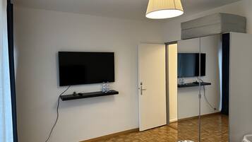 Ein Hotelzimmer mit Flachbildfernseher an der Wand, einer Tür und einem Spiegel.