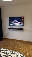 Un televisor montado en la pared con un estante debajo.