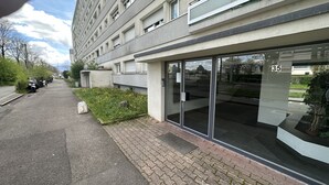 A modern building with a glass entrance, numbered 35, and a paved area with parked motorcycles and a small garden. - Quartier de Meyrin (Meyrin)