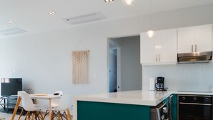 A modern kitchen with white cabinets, a teal island, and a patterned floor. - Casa Love 1D (Panama City)