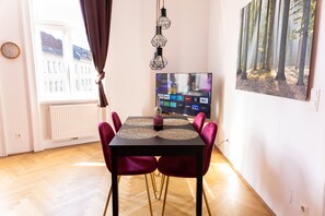 Uma área de refeições com uma mesa, cadeiras e uma tela de TV exibindo diversos logotipos.