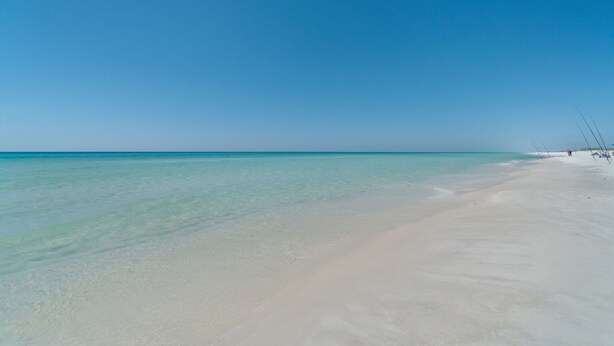 Een strand met helder turquoise water en een zandstrand.