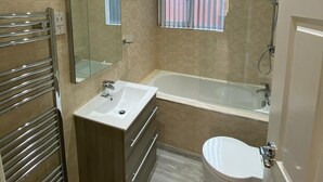 Et moderne badeværelse med en glasbrusekabine, et fristående badekar og et toilet.