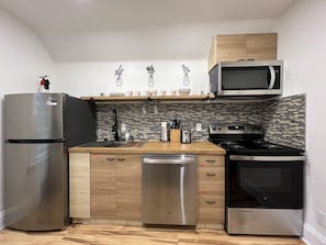 Una cucina moderna con elettrodomestici in acciaio inossidabile, mobili in legno e zoccolo a mosaico.